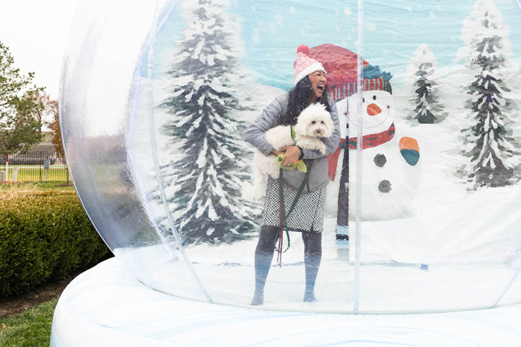 Dr. G holding dog and laughing in an inflatable snow globe