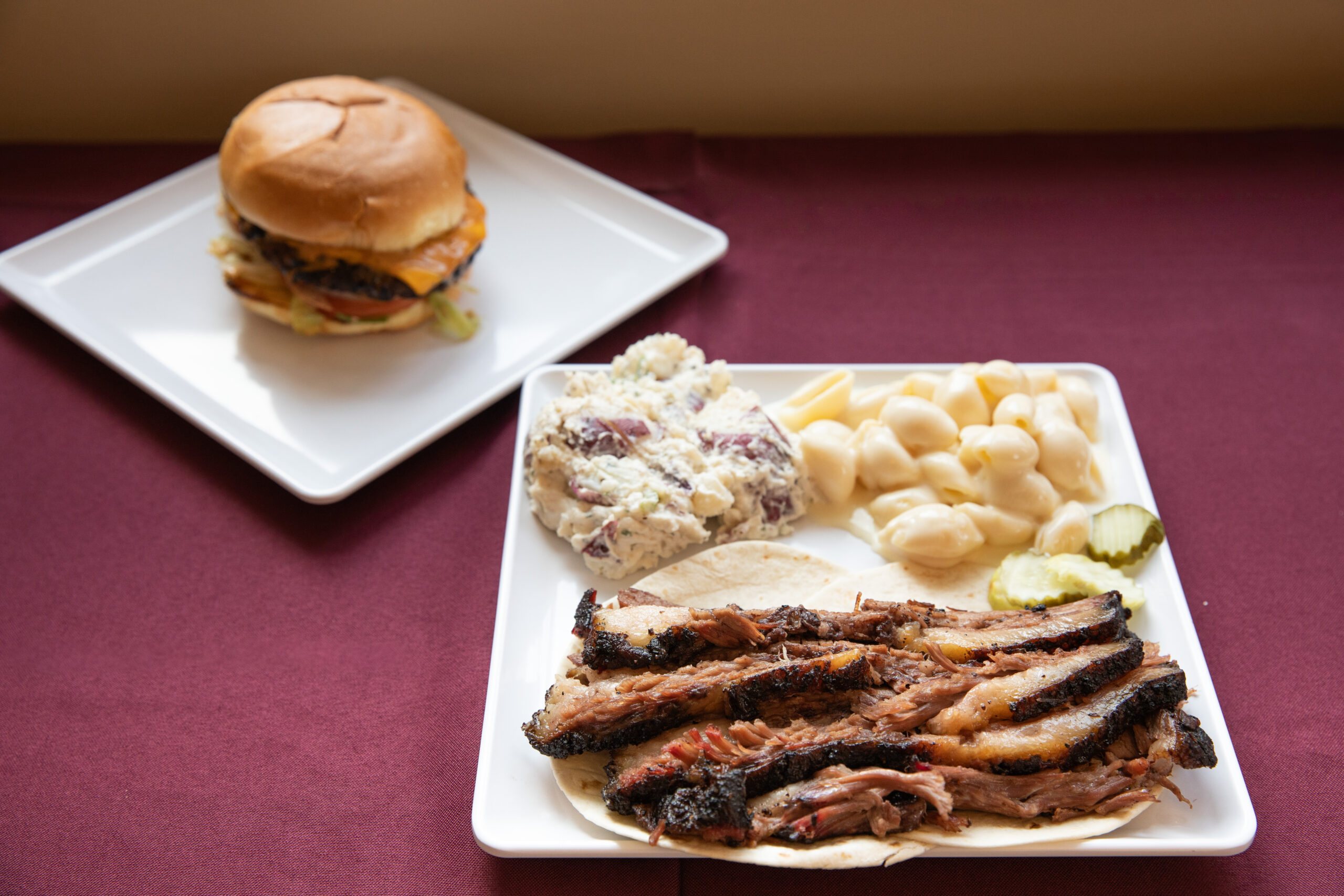 A plate with smoked brisket, mac and cheese, and mashed potatoes.