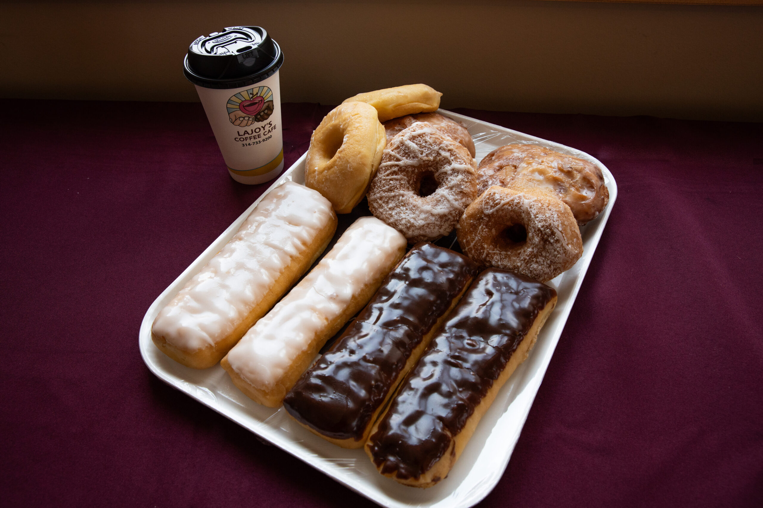 A tray of pastries and a disposable coffee cup