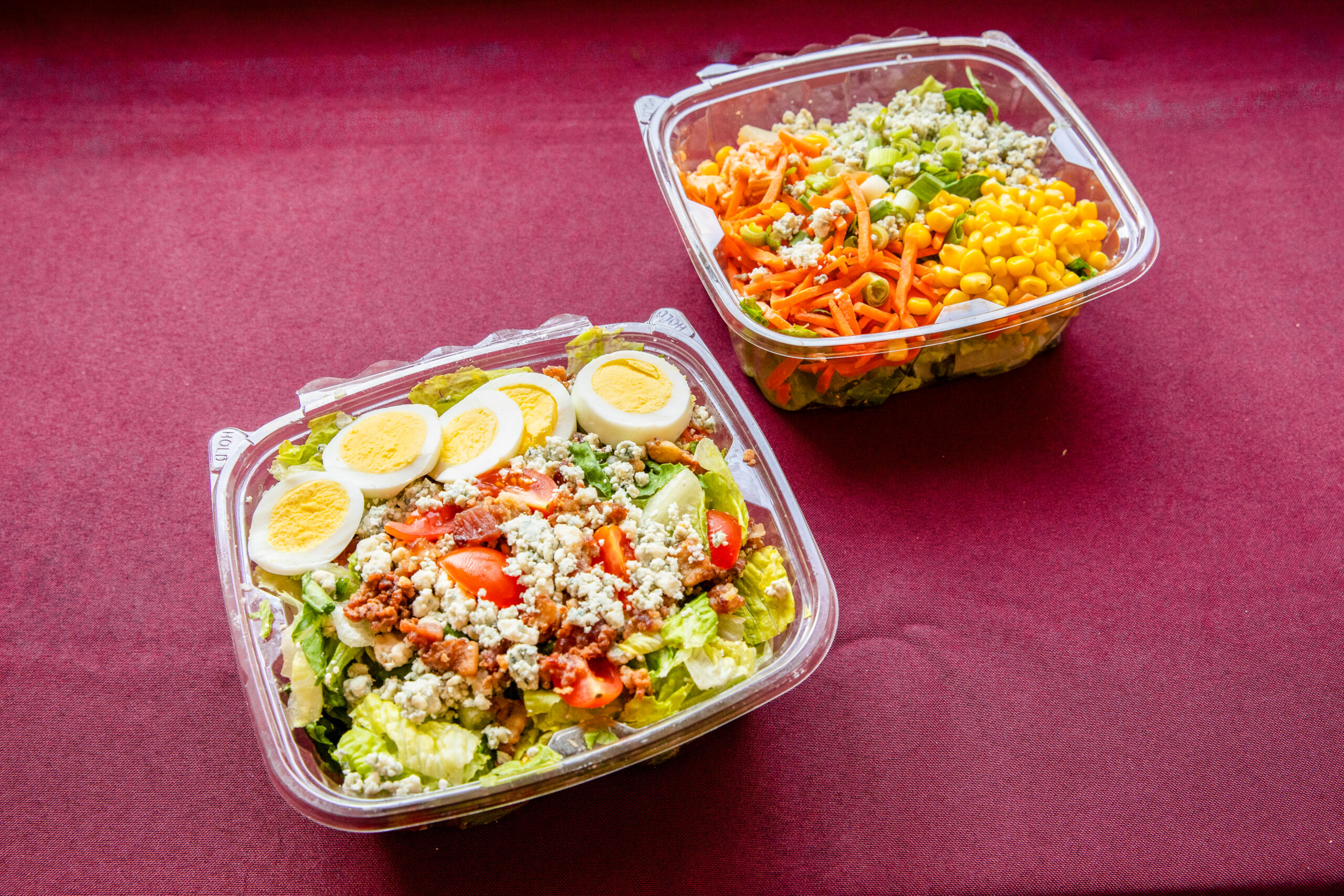 A Buffalo Chicken Salad and Cobb Salad, both in plastic bowls.