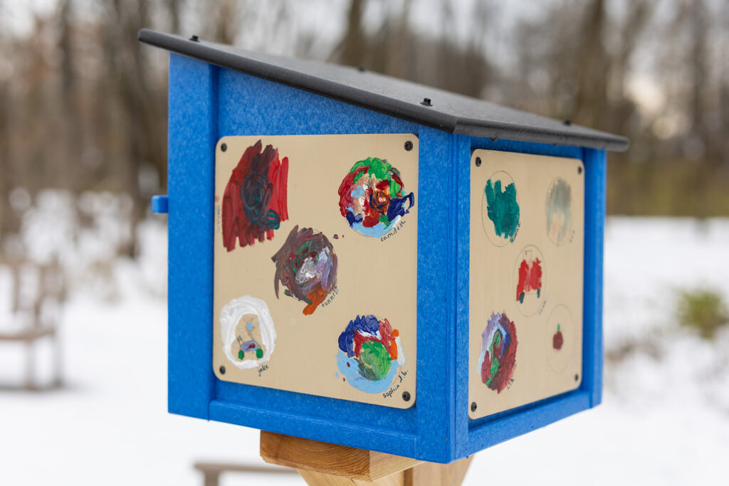 A close-up photo of the Little Free Library, showing its decorations done by local preschool children. 